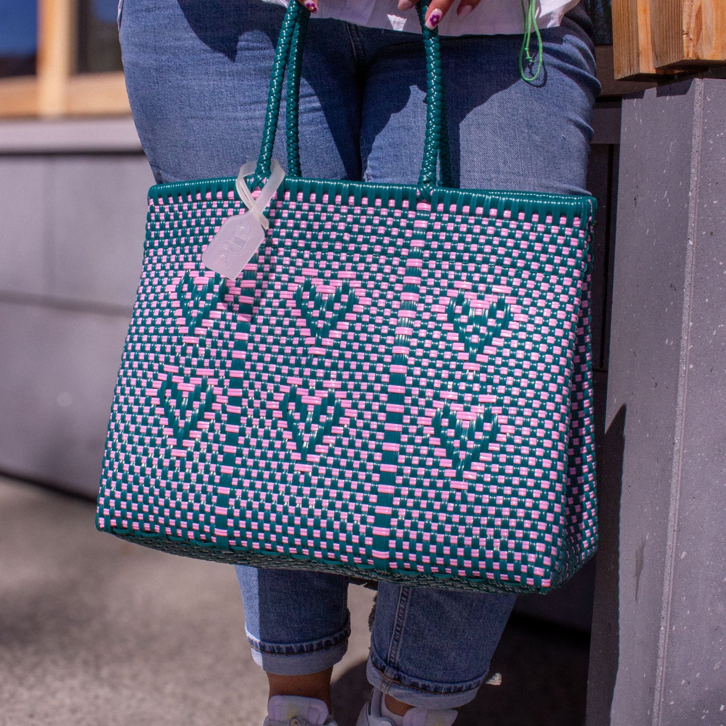 Plan rapproché sur le tressage du sac Chéri M Calista, motif cœurs vert et rose en plastique recyclé.