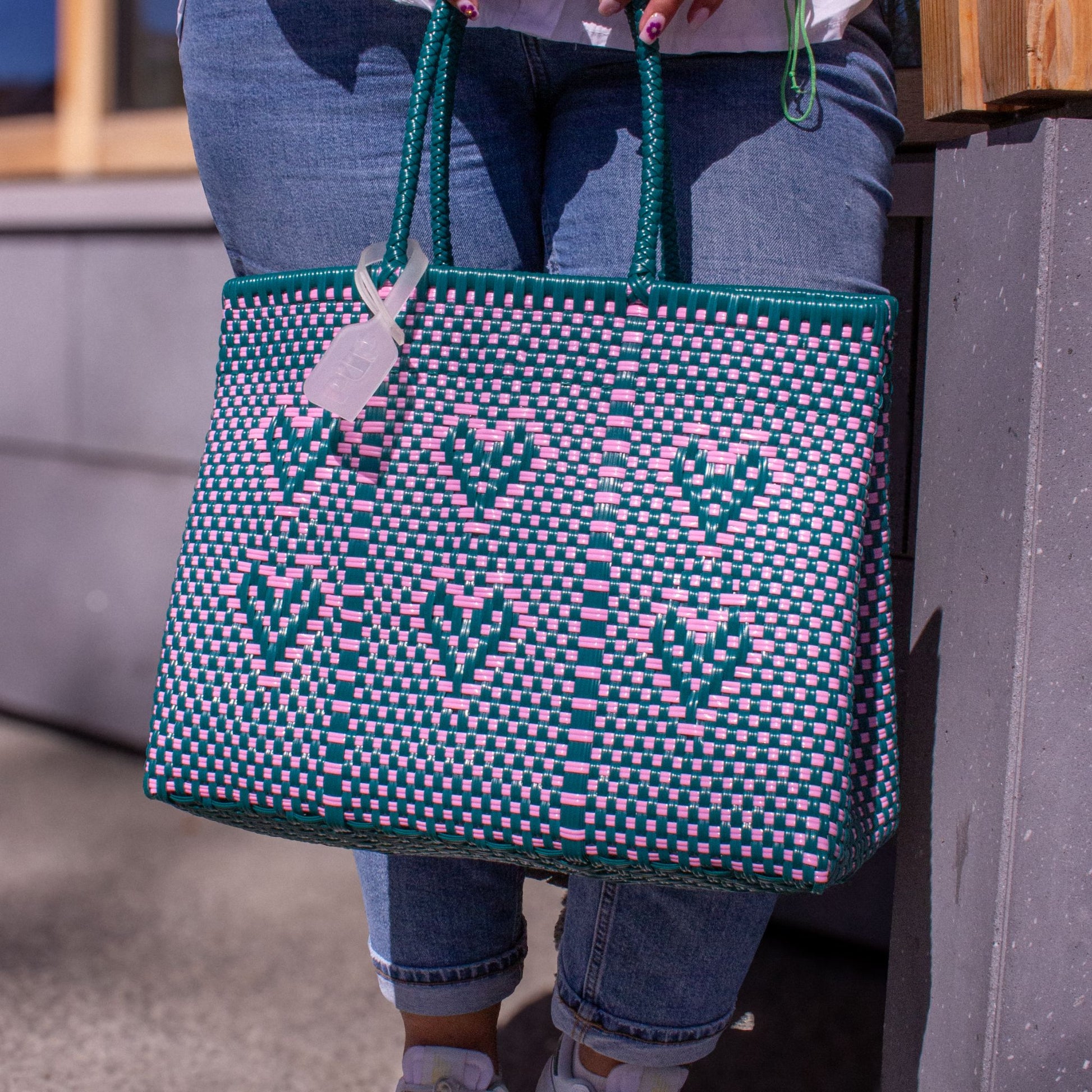 Plan rapproché sur le tressage du sac Chéri M Calista, motif cœurs vert et rose en plastique recyclé.