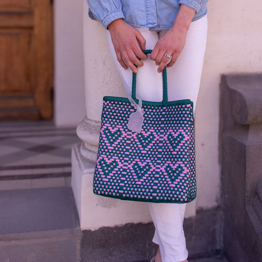 Plan rapproché du sac Chéri S Calista, dévoilant ses détails tressés verts et roses et ses cœurs.