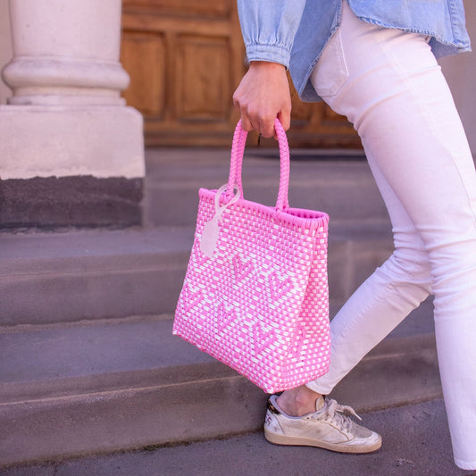 Plan rapproché du sac Chéri M Calypso, mettant en valeur son motif cœurs et ses tons rose et blanc.