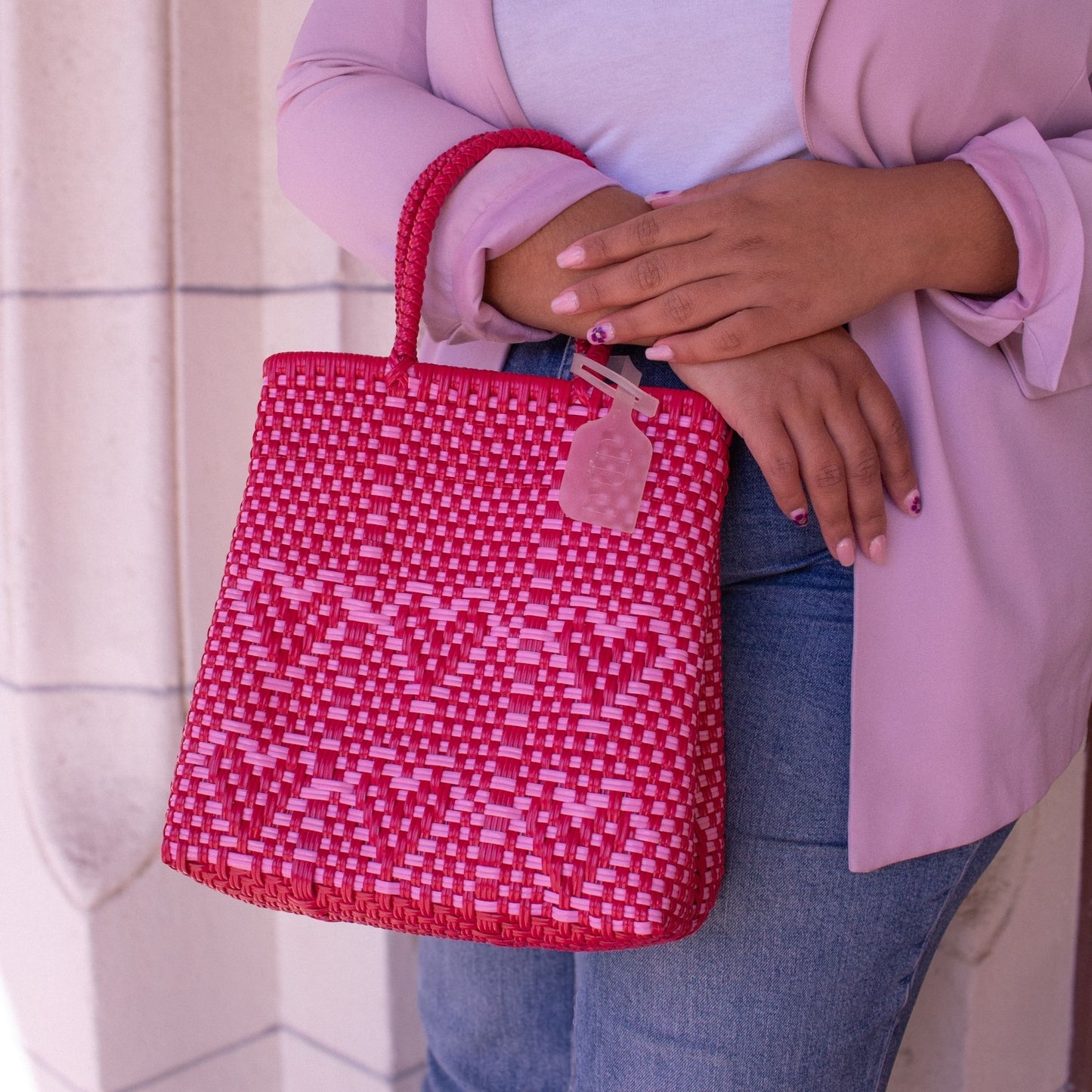 Plan rapproché du sac Chéri S Camélia, révélant ses détails tressés en plastique recyclé, rose et rouge.