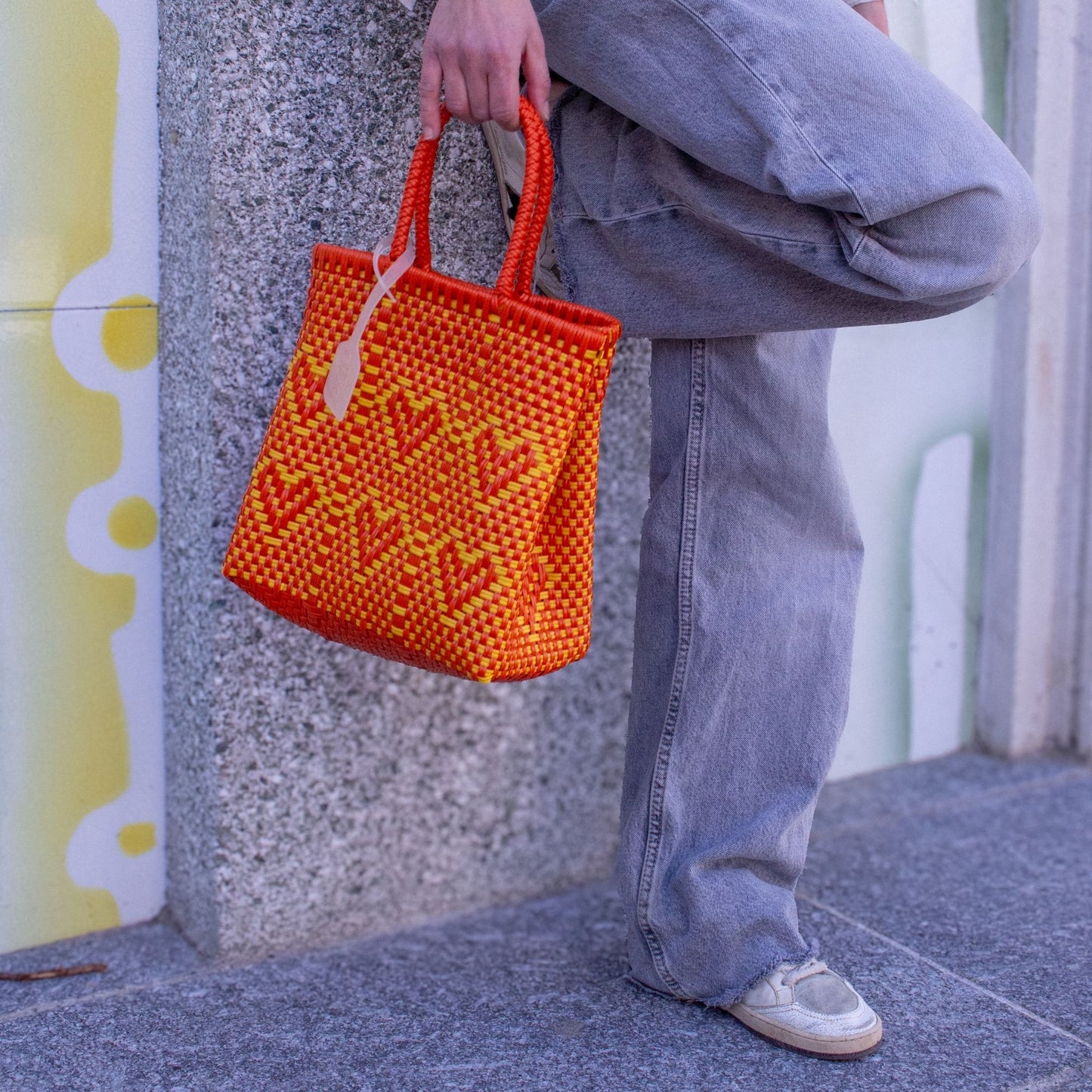 Plan rapproché du sac Chéri S Capucine, mettant en avant son tressage orange et jaune et ses jolis cœurs.