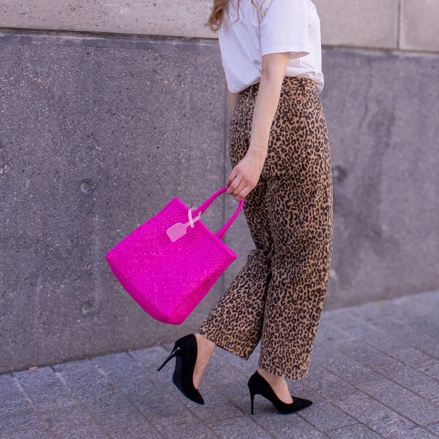 Emmanuelle porte le sac Loom S Bougainvillier, tressé en plastique recyclé, dans une teinte rose éclatante.