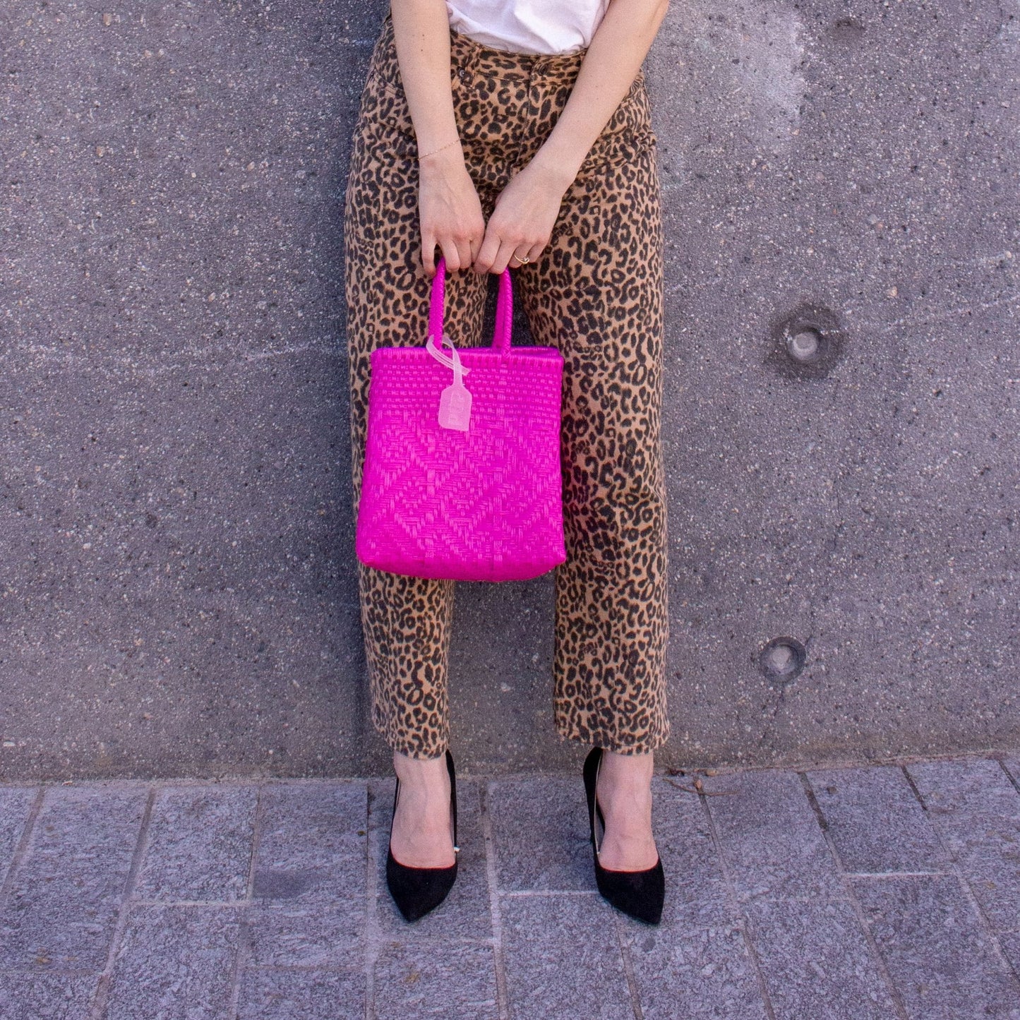 Le sac Loom S Bougainvillier, rose et tressé en plastique recyclé, porté par Emmanuelle.