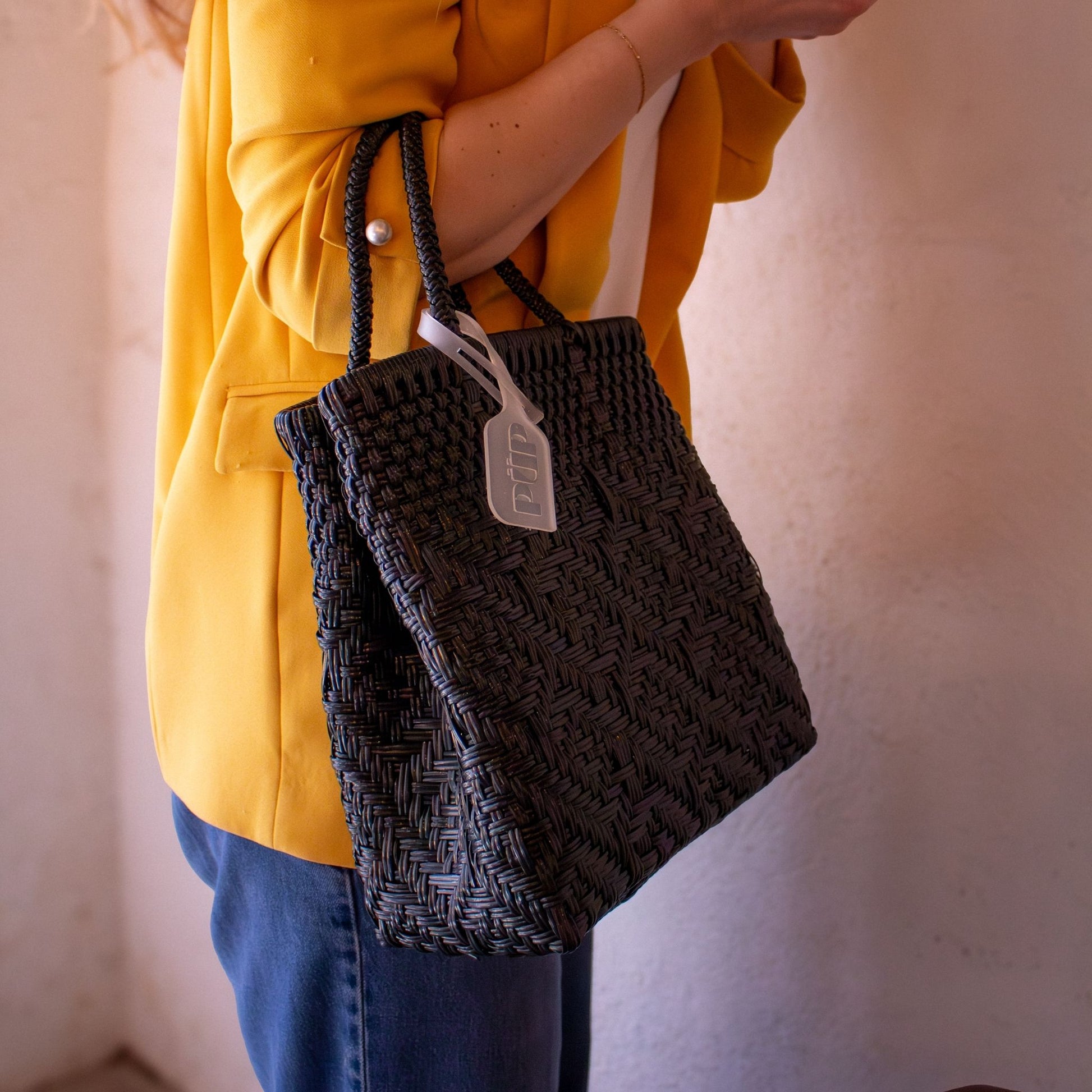 Plan rapproché du sac Loom S Charbon, dévoilant son tressage noir en plastique recyclé.