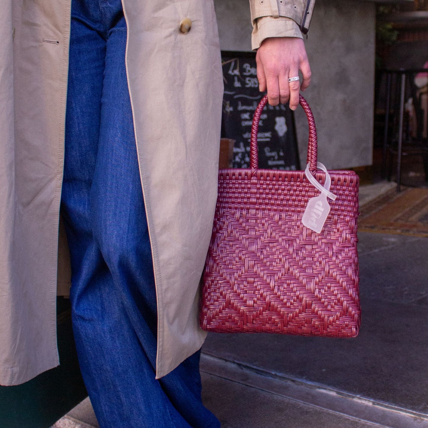 Anna tient le sac Loom S Lie de Vin, montrant son tressage soigné et sa teinte bordeaux.
