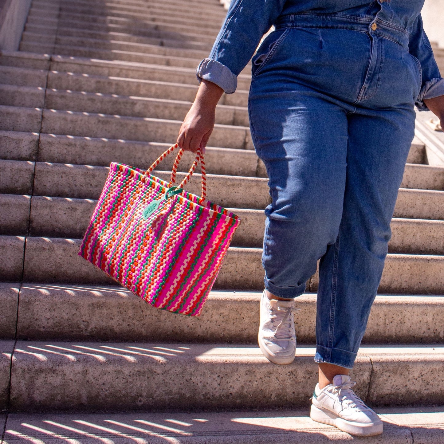 Madie fait balancer son panier Medium Tutti Frutti en plastique recyclé aux couleurs vives.