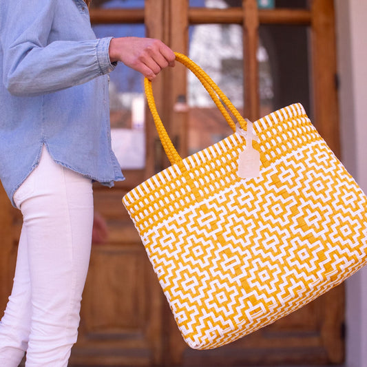 Plan rapproché sur le sac Mosaïc M Aurore, dévoilant son tressage lumineux en blanc et jaune.