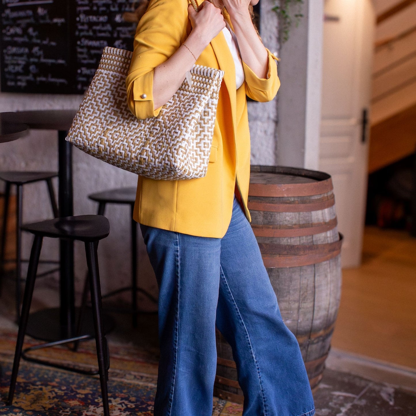 Emmanuelle arbore le sac Mosaïc M Dune, blanc et beige, tressé en plastique recyclé, pour une allure minimaliste.