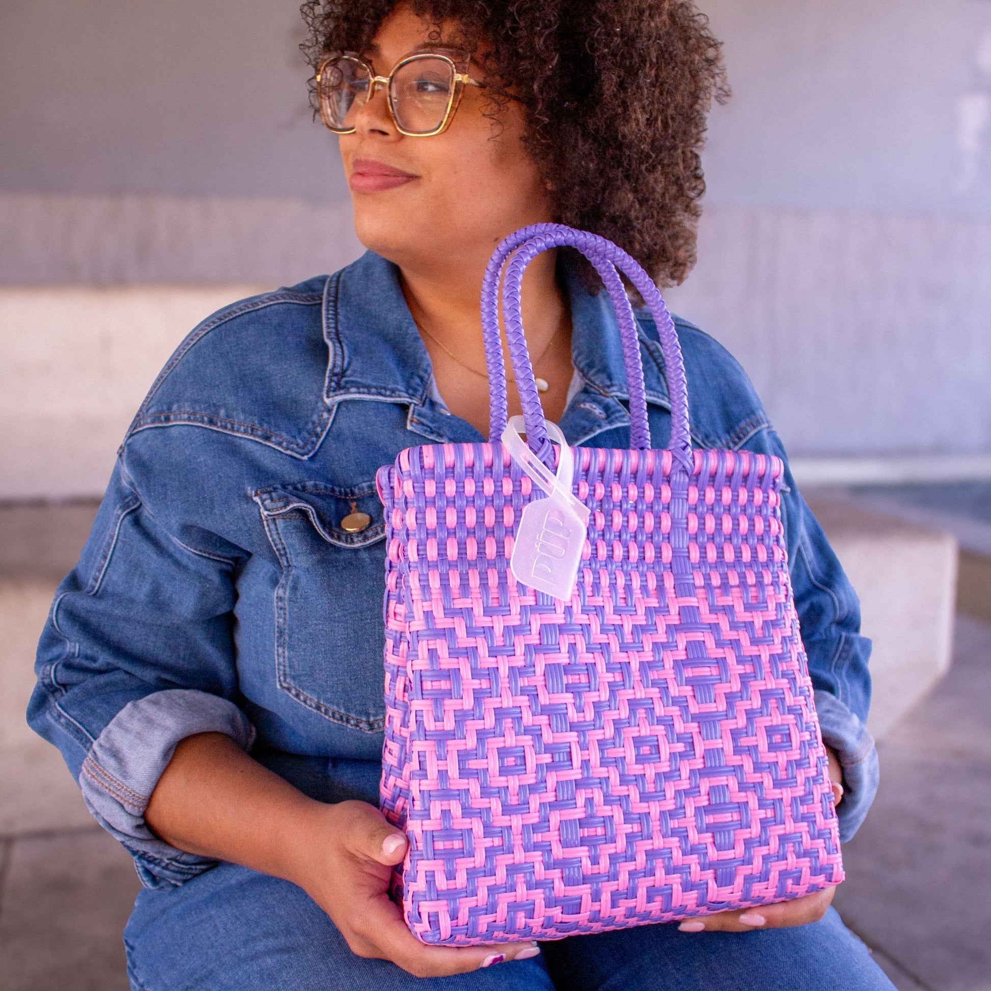 Madie porte le sac Mosaïc S Althéa, tressé en plastique recyclé dans un duo de teintes rose et violet.