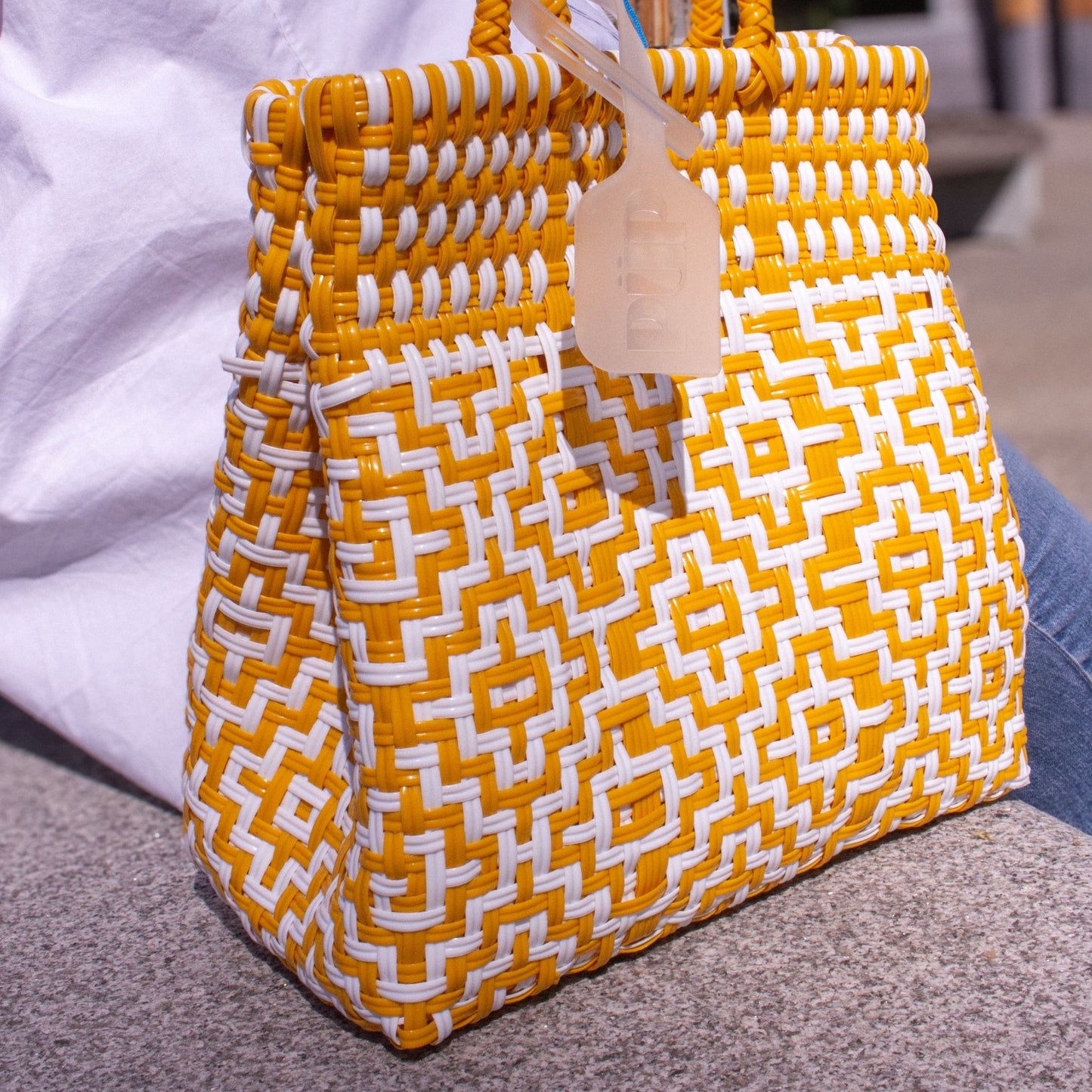 Plan rapproché du sac Mosaïc S Aurore, révélant la finesse de son tressage blanc et jaune.