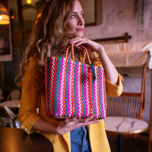 Emmanuelle tient entre ses mains le panier Small Tutti Frutti en plastique recyclé multicolore.