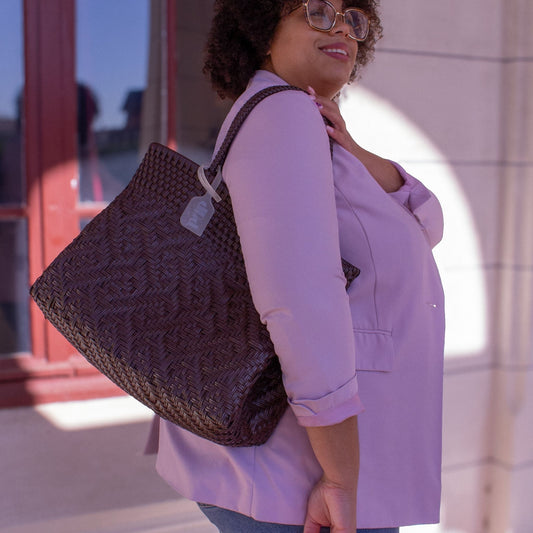 Le sac Loom M Chocolat, marron et tressé en plastique recyclé, complète la tenue féminine de Madie.