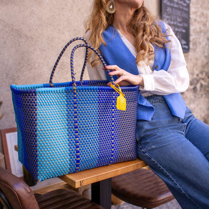 Emmanuelle est installée au café avec son panier Maxi Nox en plastique recyclé dégradé de bleu.