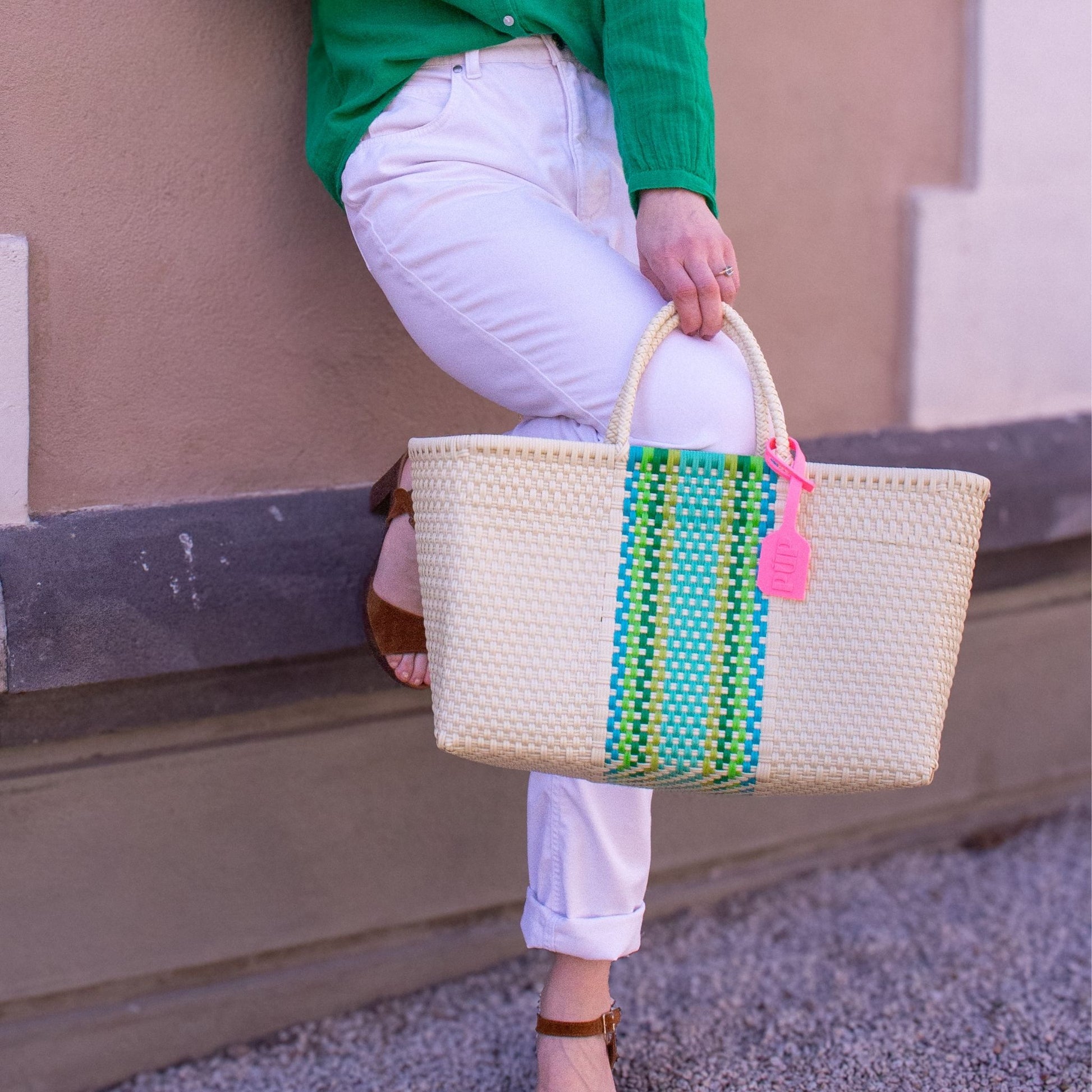 Panier Medium Verveine porté à la main d'Emmanuelle, avec son bandeau central vert et bleu.