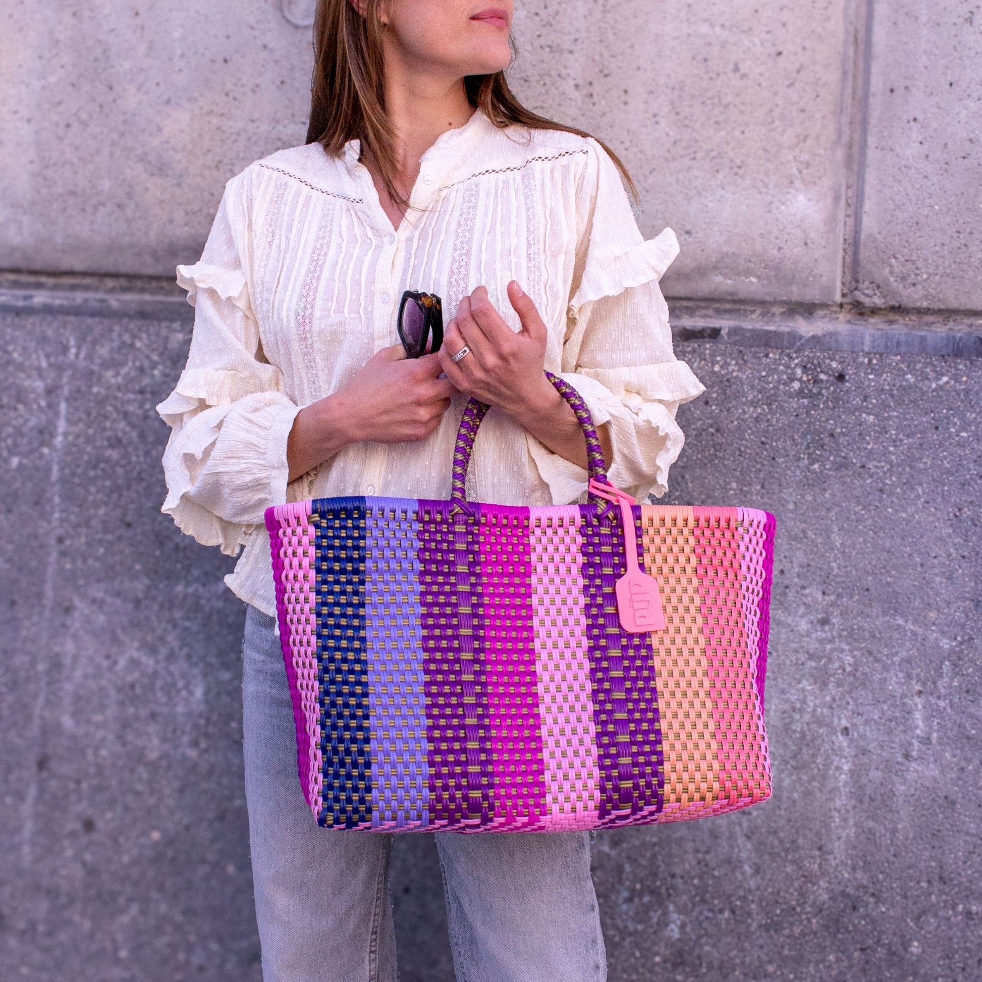 Vue du panier Medium Vespera porté par Anna, tressage en plastique recyclé aux nuances violettes et rosées.